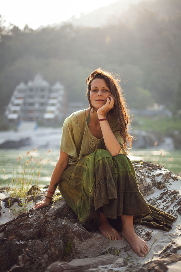 Eine Frau sitzt auf einem Stein in der Natur in Indien - Katharina Treder Heilpraktikerin für Psychotherapie
